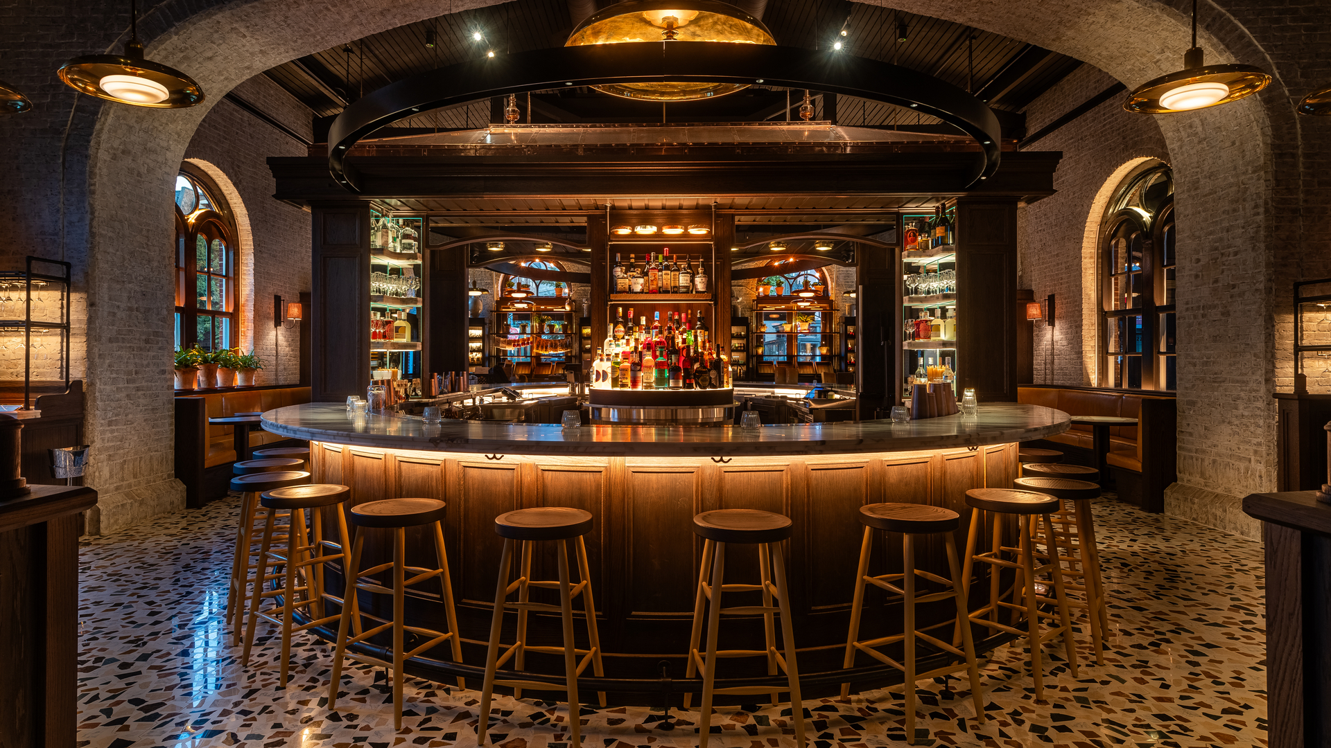 Spacious, modern bar with high stools and warm lighting, set against a marble-tiled floor.